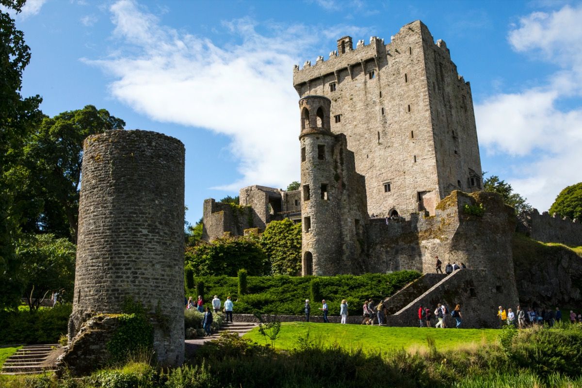 средновековен замък в Ирландия с туристи на поляната му