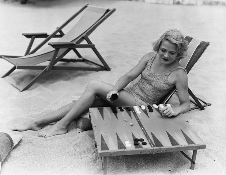 egy nő backgammonot játszik a tengerparton