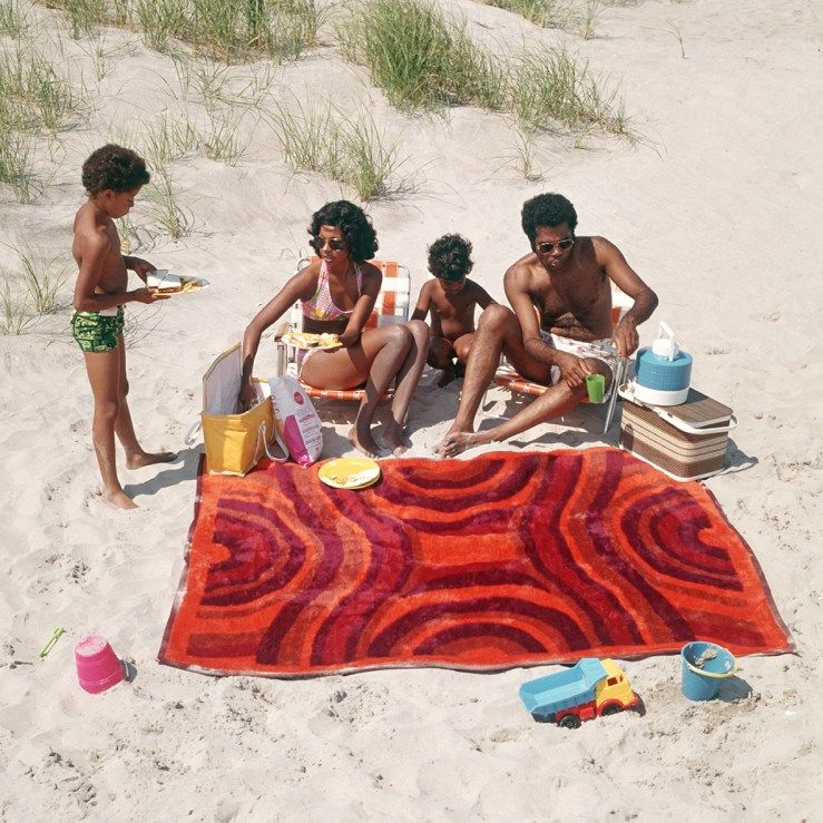 una família de quatre persones fa un pícnic a la platja als anys setanta