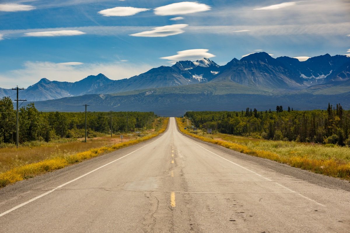 uma estrada leva a uma cadeia de montanhas no Alasca no verão