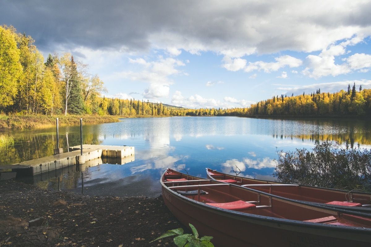 Kai ja kaks punast kanuud Talkeetna järvedel, avatud järv, sügispuud ja pilvede peegeldus.