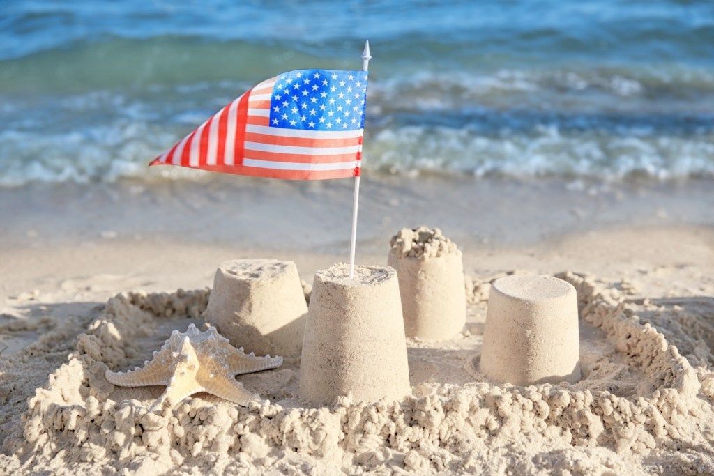 महासागरों के बारे में समुद्र तट के तथ्यों पर रेत महल में अमेरिकी ध्वज