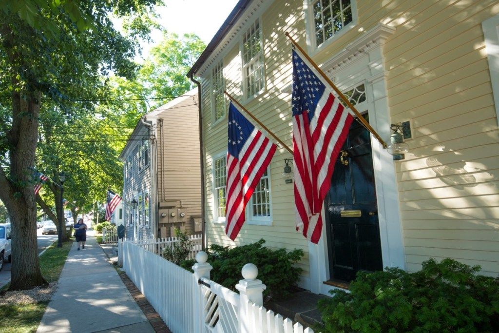 ESSEX, CONNECTICUT, ASV - 2018. gada 19. jūnijs: Amerikas karogi un balta žoga līnija Main Street, Eseksā, visas Amerikas ciematā. - attēls