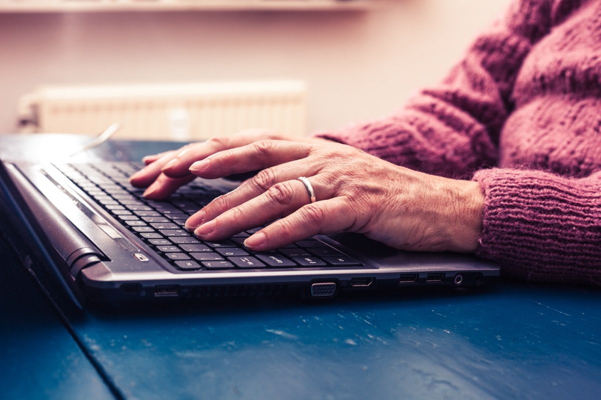 Vyresnė moteris rašo nešiojamuoju kompiuteriu