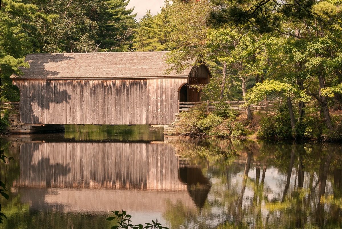 крытый деревянный мост, отражающийся в воде
