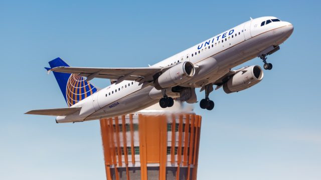   Et United Airlines-fly letter fra lufthavnen med et flyvekontroltårn i baggrunden