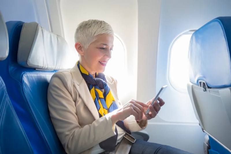   אשת עסקים משתמשת בטלפון חכם במטוס