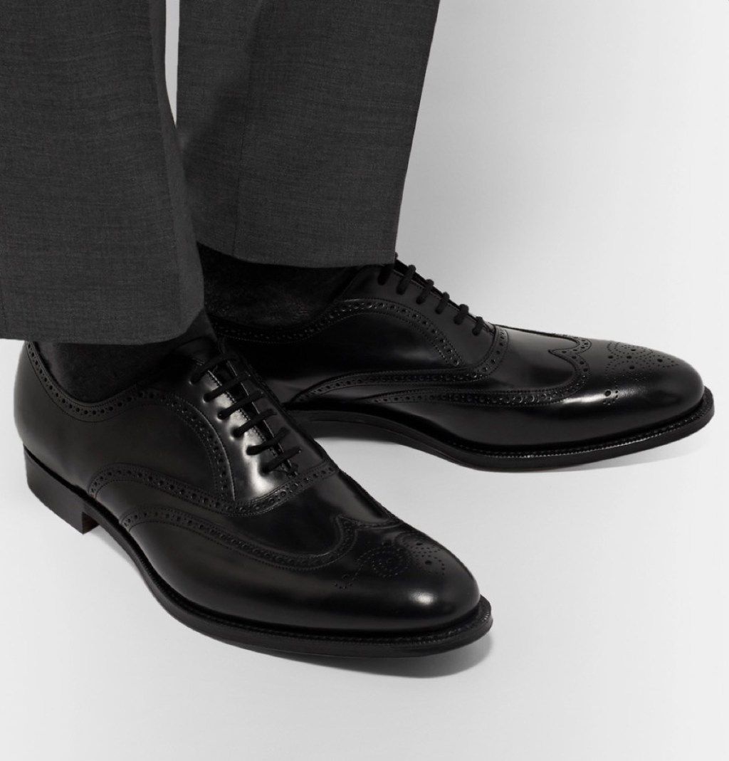 आदमी ग्रे पैंट और काले चमकदार जूते पहने हुए