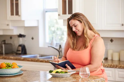   Ženska piše v dnevnik hrane, preden poje svoj obrok